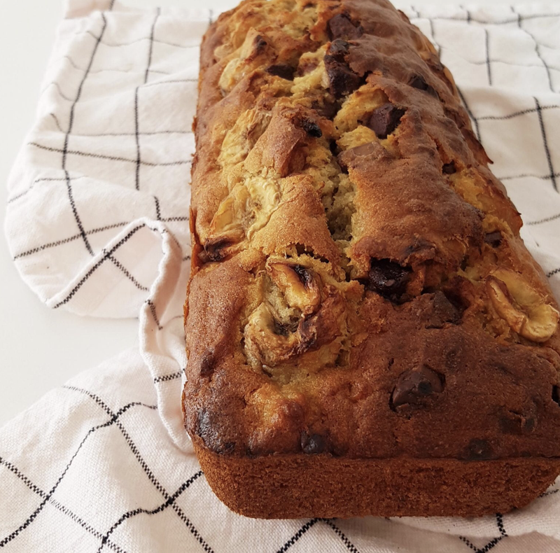 a chocolate banana bread on a kitchen towel, view from side. With round
banana slices
and chocolate chunks visible in the dough.